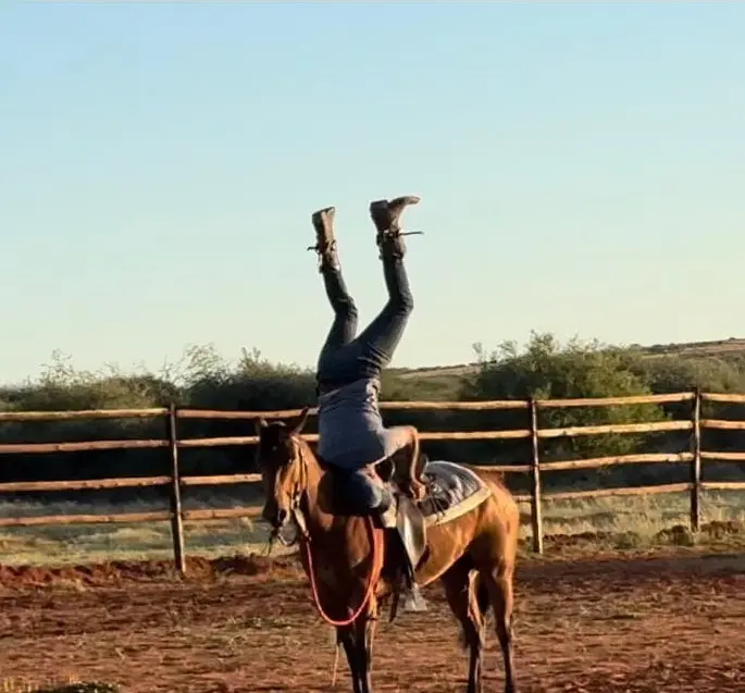 Kruger Snyman riding a horse while standing on his head.
